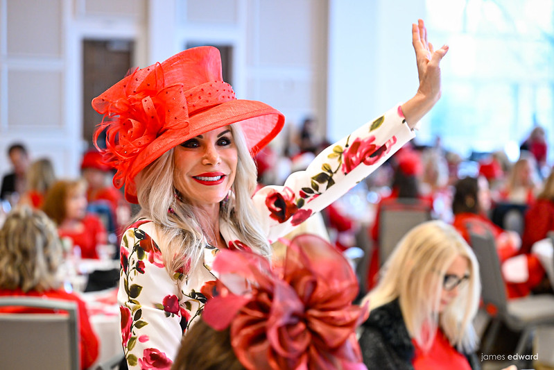 Woman in large red hat holding her hand up