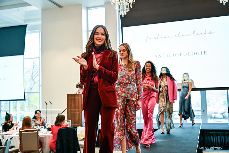 Five models walking down runway with screen reading fashion looks by Anthropologie in the background